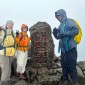 Three hikers pose on the summit of a mountain