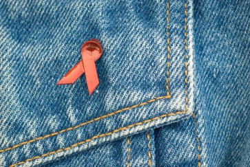 An HIV awareness ribbon on a denim background