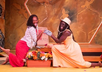 Two women clasp hands and smile during a scene in Honeypot