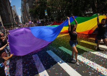 People carry a large pride flag during a parade