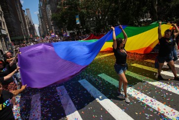 People carry a large pride flag during a parade