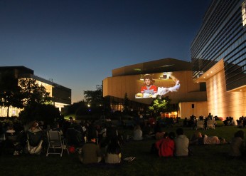 Summer Cinema attendees watch a movie on the Arts Green Lawn at dusk