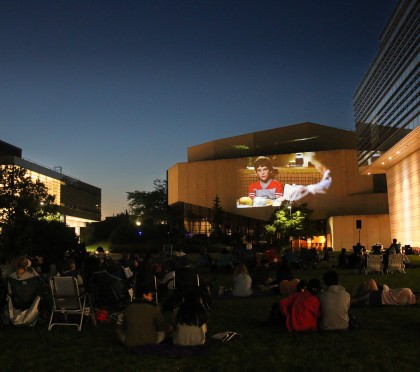 Summer Cinema attendees watch a movie on the Arts Green Lawn at dusk