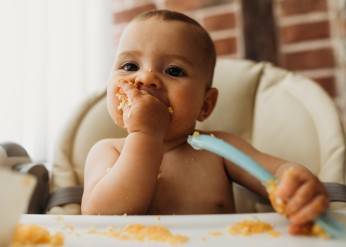 A baby eats in a high chair