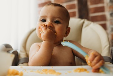 A baby eats in a high chair