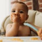 A baby eats in a high chair