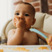 A baby eats in a high chair