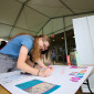 A student works on a posterboard for the Tabletop Club ahead of a previous org fair