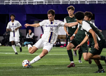 A Northwestern men's soccer player winds up for a kick as three opponents look on