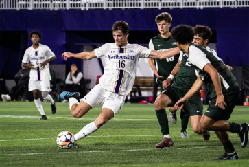 A Northwestern men's soccer player winds up for a kick as three opponents look on