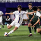 A Northwestern men's soccer player winds up for a kick as three opponents look on