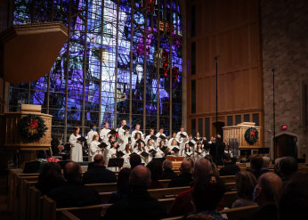 A choir sings at the front of a chapel 