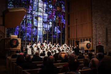 A choir sings at the front of a chapel 
