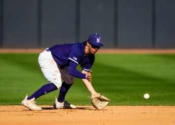 A Wildcat baseball player bends to catch a ball