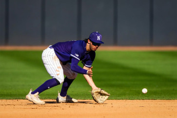 A Wildcat baseball player bends to catch a ball