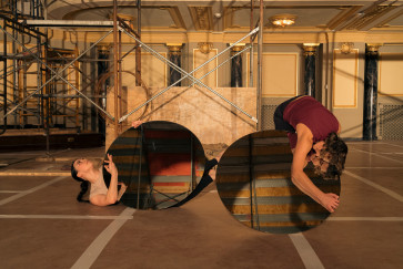 Three dancers onstage at the Driehaus Museum, two hold circular mirrors reflecting the space