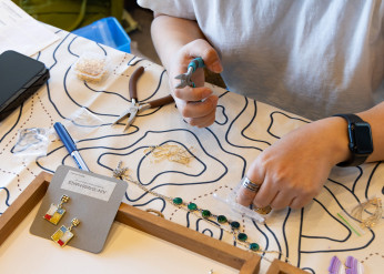 An artist's hands hold pliers while creating jewelry at last year's Spring Arts and Crafts Fair