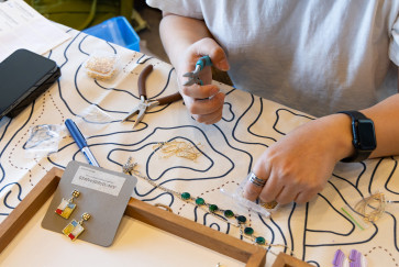An artist's hands hold pliers while creating jewelry at last year's Spring Arts and Crafts Fair