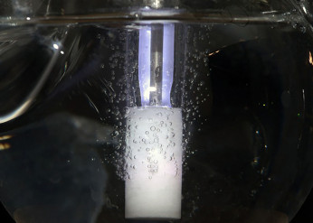 A glass tube bubbles against a black background