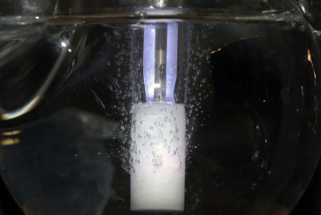 A glass tube bubbles against a black background