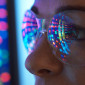 A close up of the eyes of a woman wearing safety glasses looking at a screen