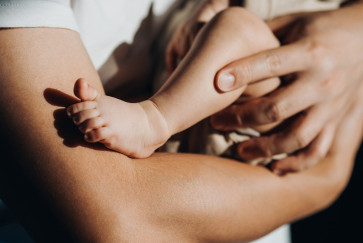 A closeup on the leg of an infant in a man's arms