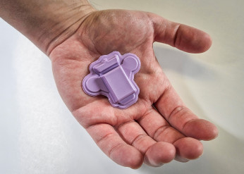 The purple wearable polygraph device rests in the palm of a hand