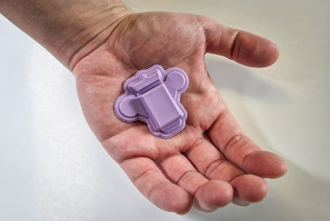 The purple wearable polygraph device rests in the palm of a hand