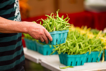 A person picks out a carton of green beans