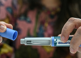 A woman's hands uncap an Ozempic auto-injector