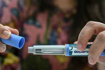 A woman's hands uncap an Ozempic auto-injector