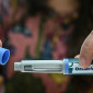 A woman's hands uncap an Ozempic auto-injector