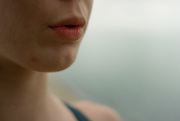 The lower half of a woman's face shows an exhaling mouth