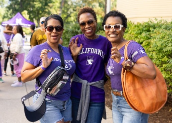 Three women in Northwestern shirts pose doing the Wildcat claw