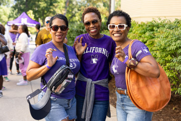 Three women in Northwestern shirts pose doing the Wildcat claw
