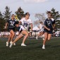A women's lacrosse player in a white Northwestern jersey runs in front of two other players in Penn State jerseys